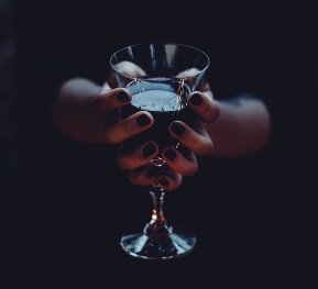 girl holding glass of wine dark setting
