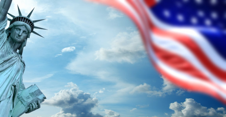 Conceptual image of waving American flag and Statue of Liberty over sky in New York