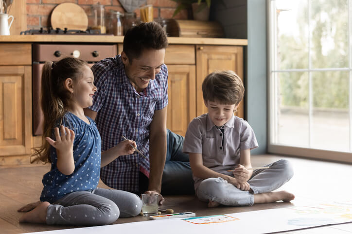 Caring dad drawing with two small kids at home