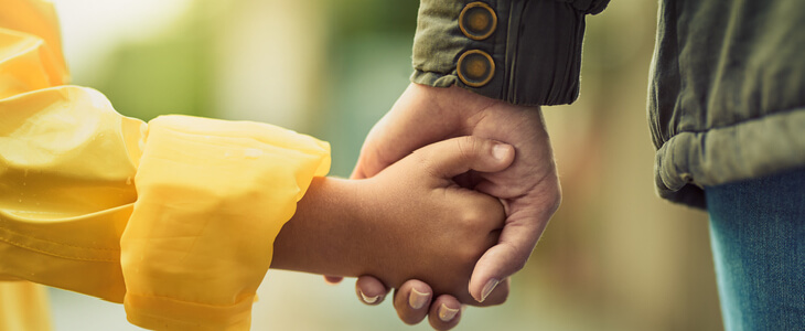 father holding hands with toddler daughter