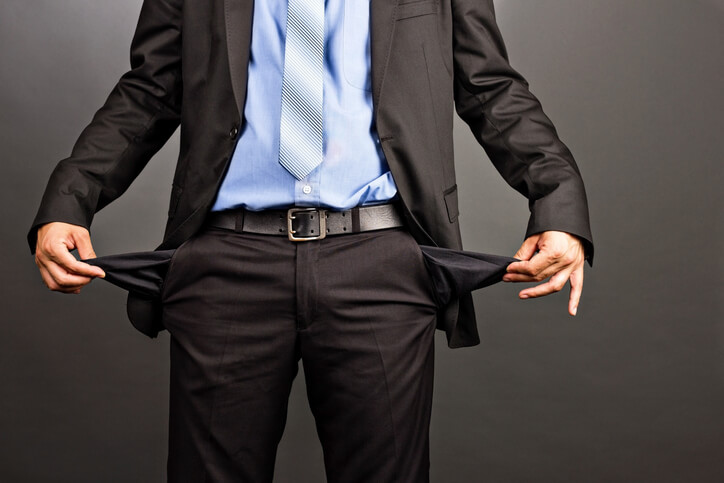 Business man showing his empty pockets on gray background