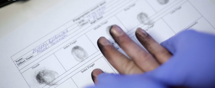 Police officer in exam gloves taking fingerprints from suspect, hands closeup