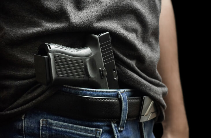 Man drawing a conceal carry pistol from a holster isolated on black background