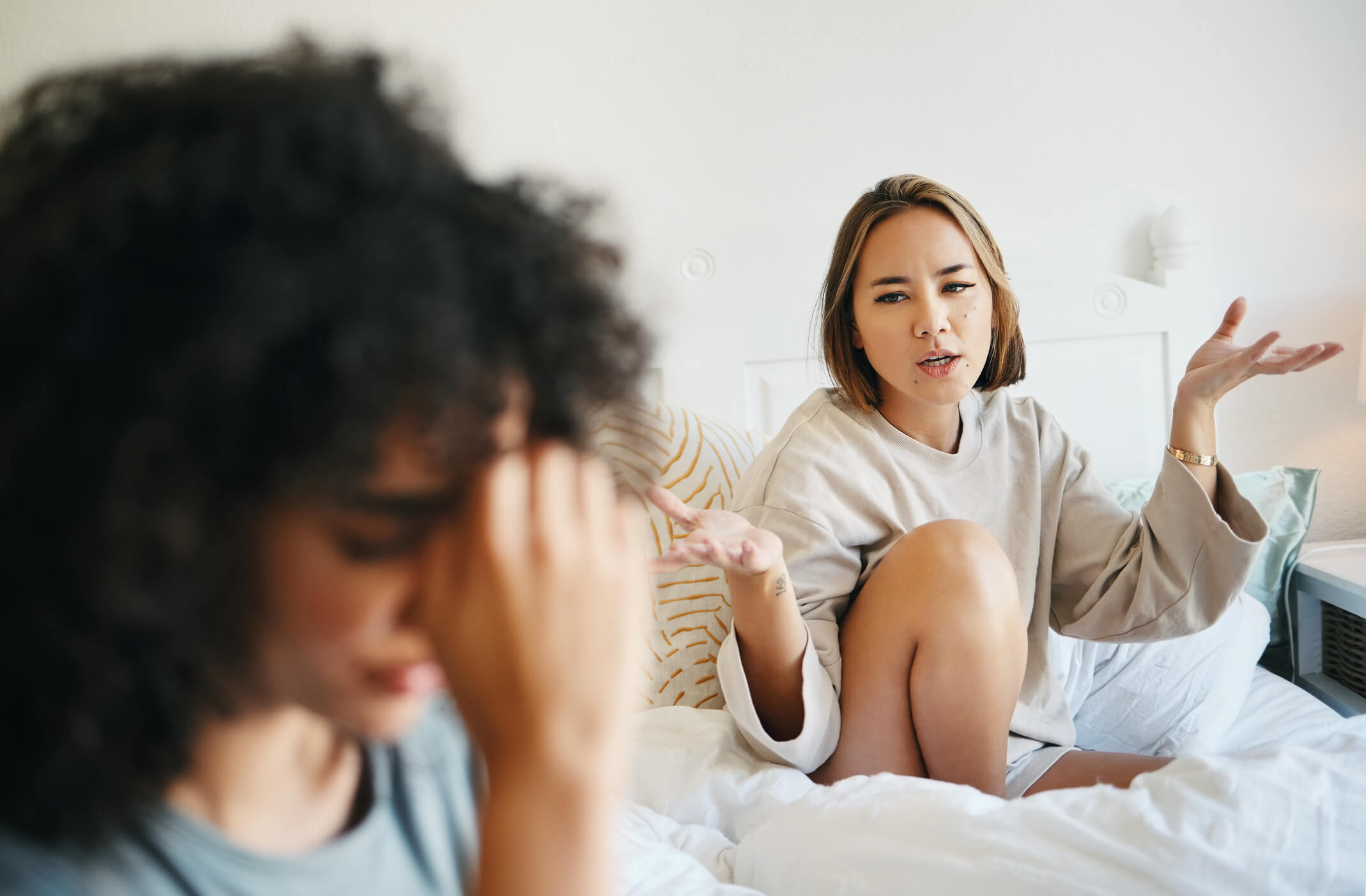 Women, lgbt couple and arguing in bed, home and talking with frustration, stress and headache. Communication, choice and sad for relationship, problems and fight for love, conversation and conflict
