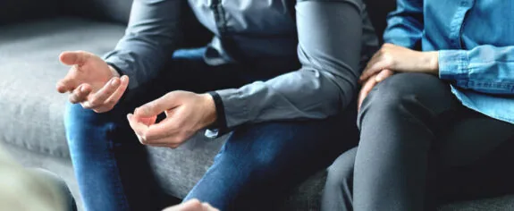 Married couple sitting down on a couch, discussing mediation with a lawyer