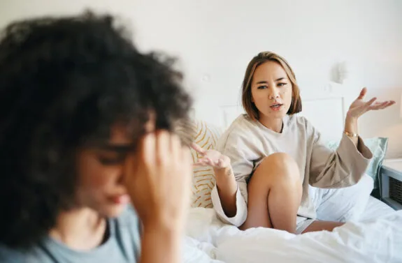 Women, lgbt couple and arguing in bed, home and talking with frustration, stress and headache. Communication, choice and sad for relationship, problems and fight for love, conversation and conflict